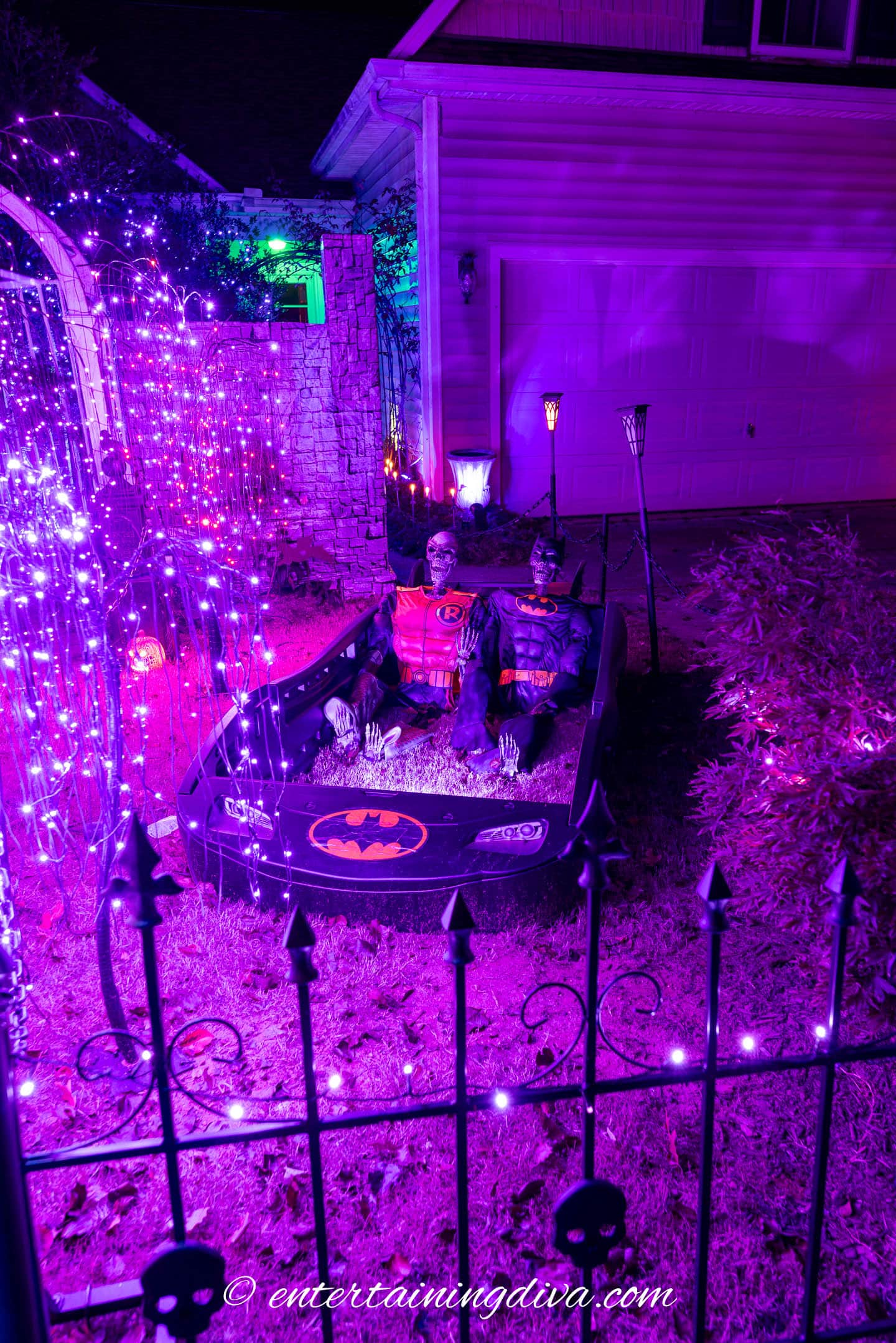 Outdoor Hallwoeen decor - Skeletons dressed as Batman and Robin inside a batmobile toddler's bed
