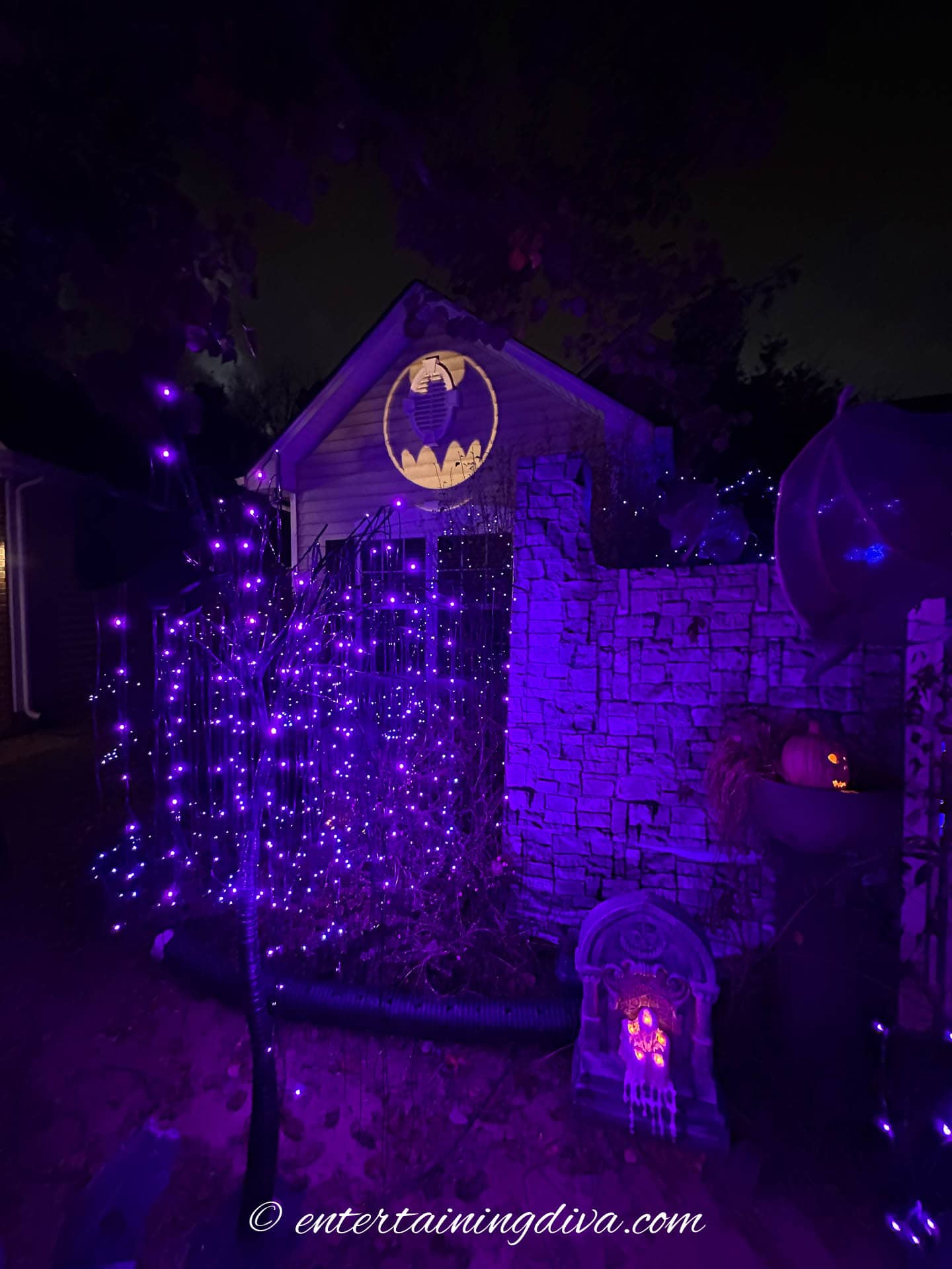 Spooky trees with purple lights and the bat signal in the background
