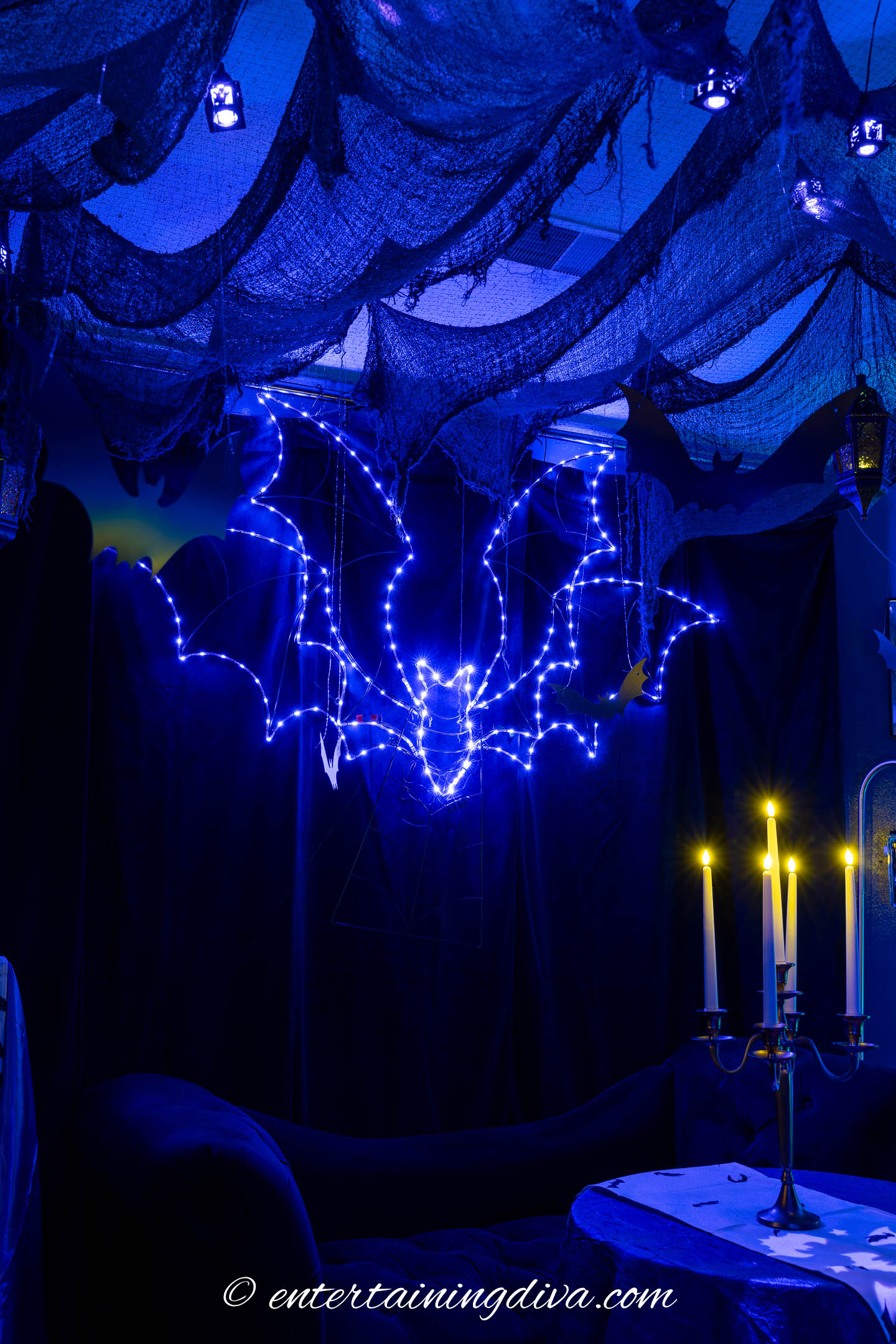 A purple lighted bat hung on the wall at an adult batman Halloween party