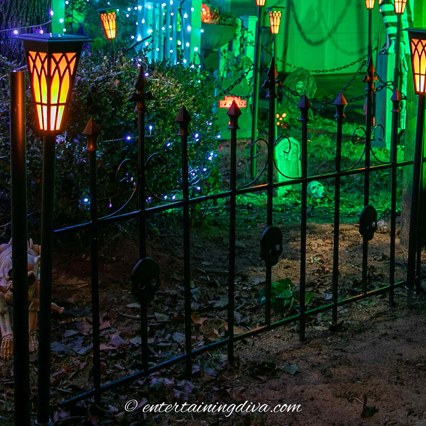 A metal fence with skulls surrounding a Halloween graveyard