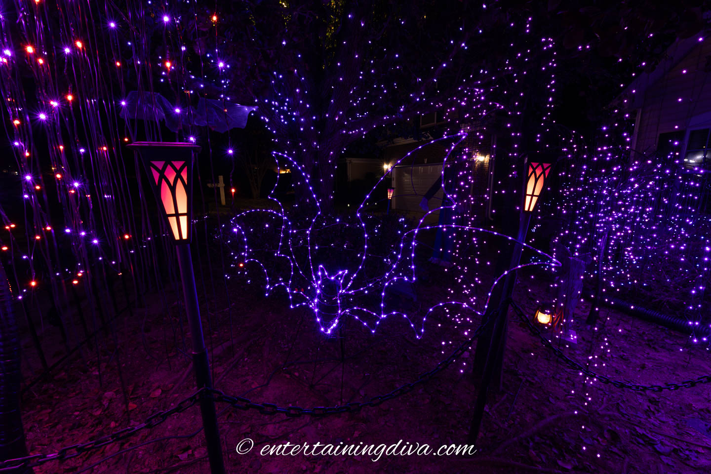 A large purple lighted bat in a Halloween yard display