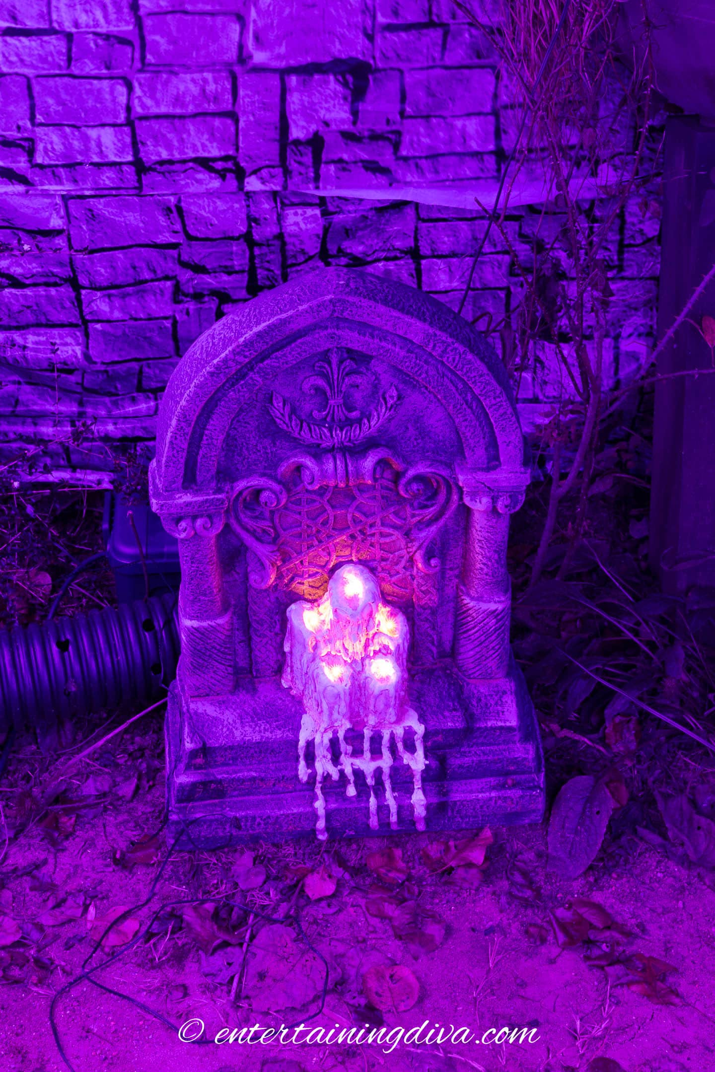 A Halloween tombstone with melting candles on the front of it