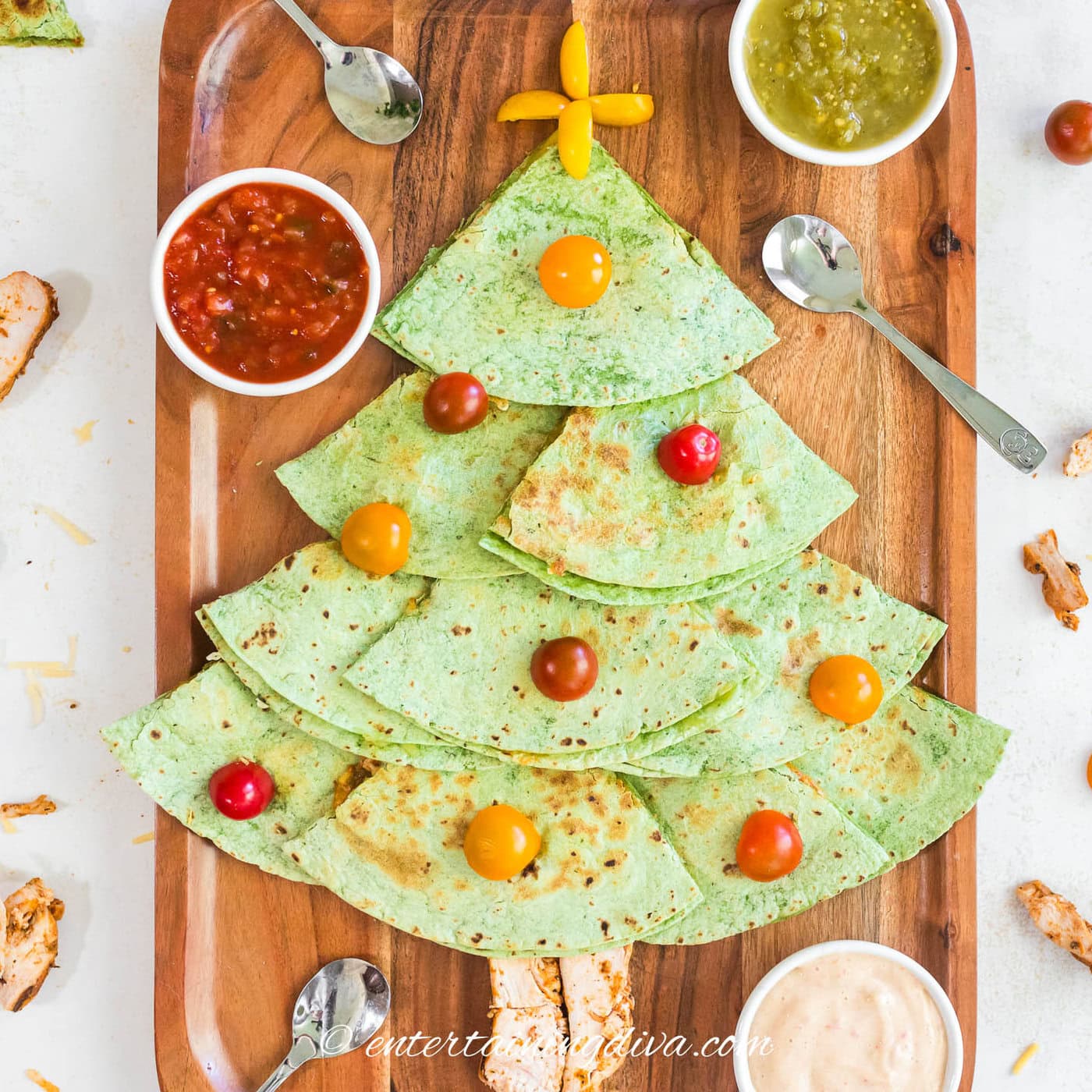 Close up of Christmas tree quesadillas on a serving tray with salsa and queso in serving bowls
