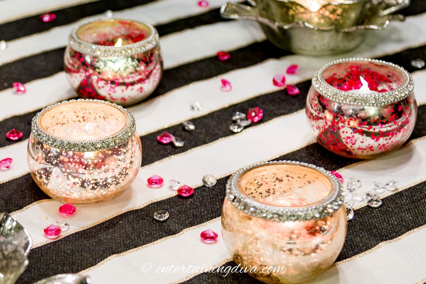 Pink and clear crystals on a black and white table setting with tea light candle holders