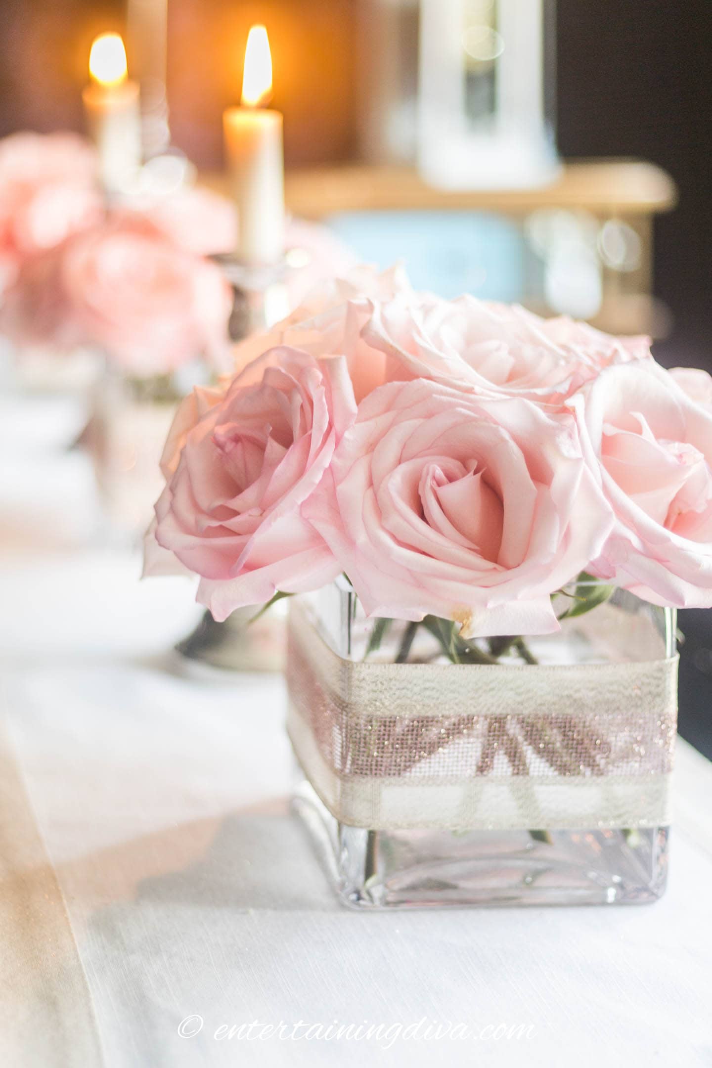 A Valentine's Day centerpiece with pink roses in a square glass vase