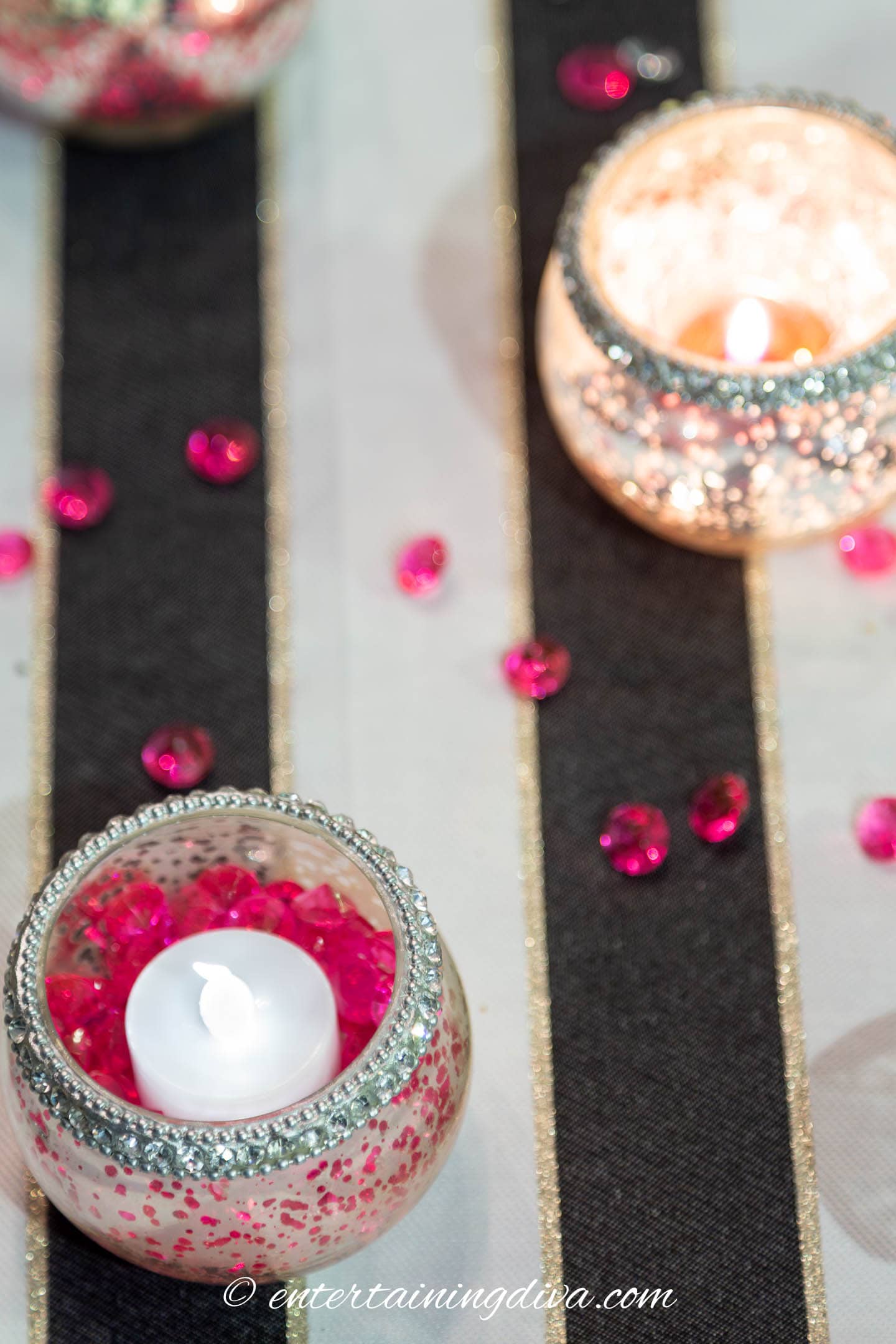 A tealight candle holder filled with pink crystals and a flameless candle
