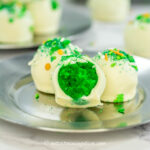 close up of a green and white cake ball decorated with St Patrick's Day sprinkles with a bite out of it