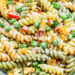 close up of creamy pasta salad with peas and bell peppers