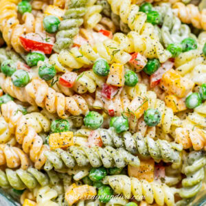 close up of creamy pasta salad with peas and bell peppers