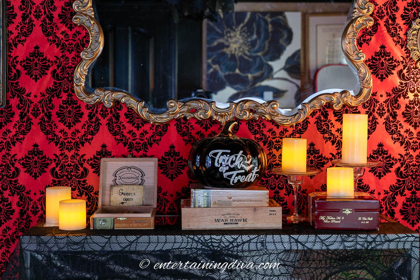 A decorated table with LED candles, cigar boxes, and a black pumpkin with