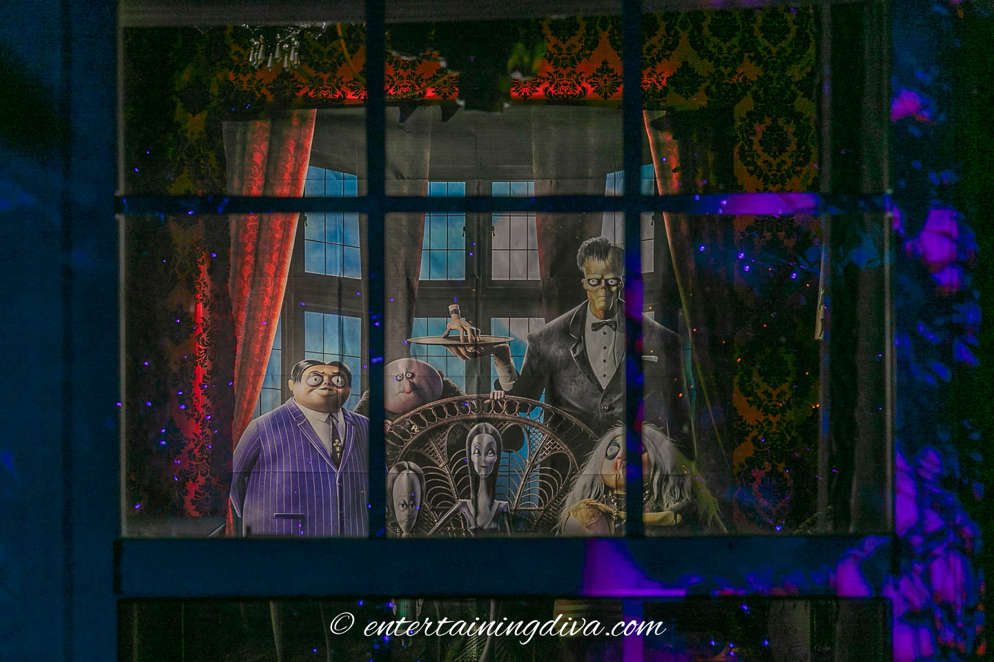 A backlit Addams Family theme party scene setter seen through a window