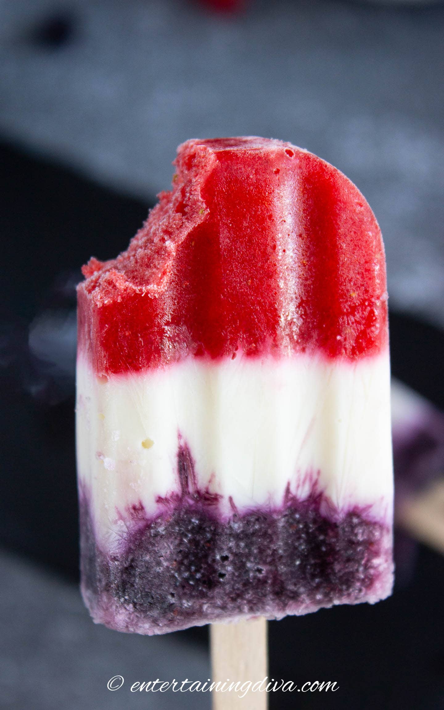 close up of a red, white and blue 4th of July popsicle with a bite taken out of it