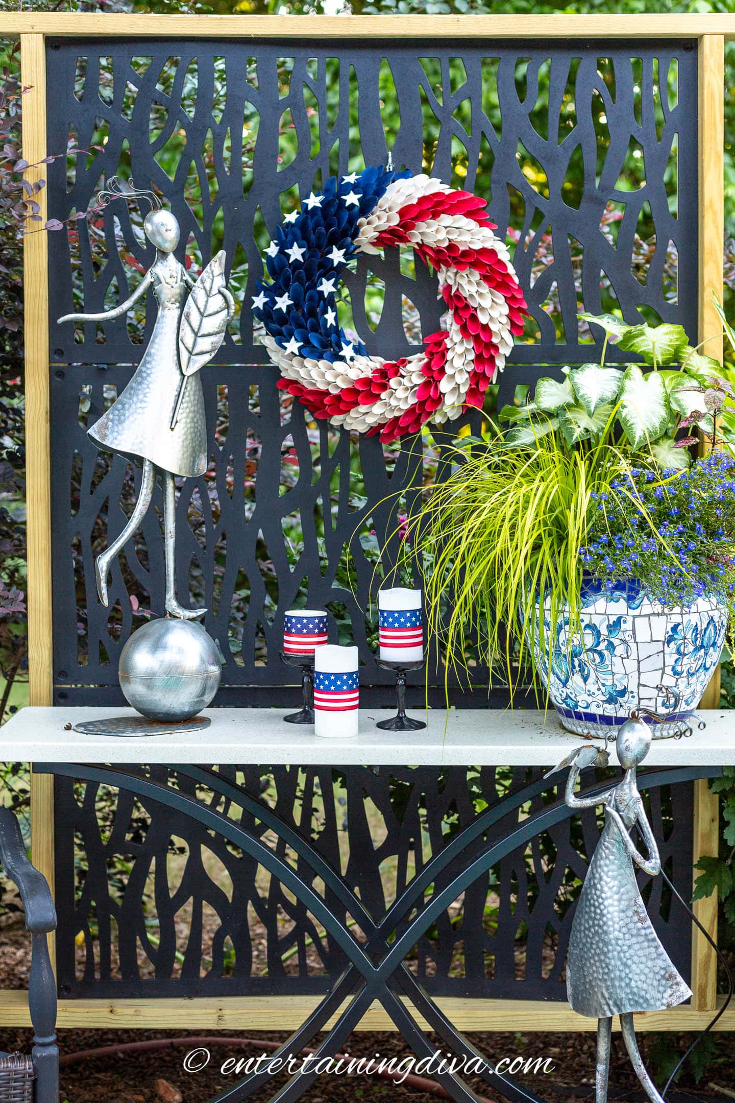 an outdoor privacy screen with a 4th of july wreath and candles on a table in front of it