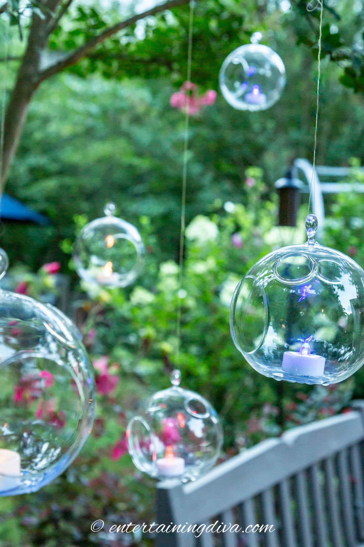 Red, white and blue flameless tealights hung in terrarium candle holders in the garden