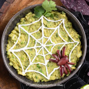 Halloween guacamole decorated with a sour cream spider web and spider