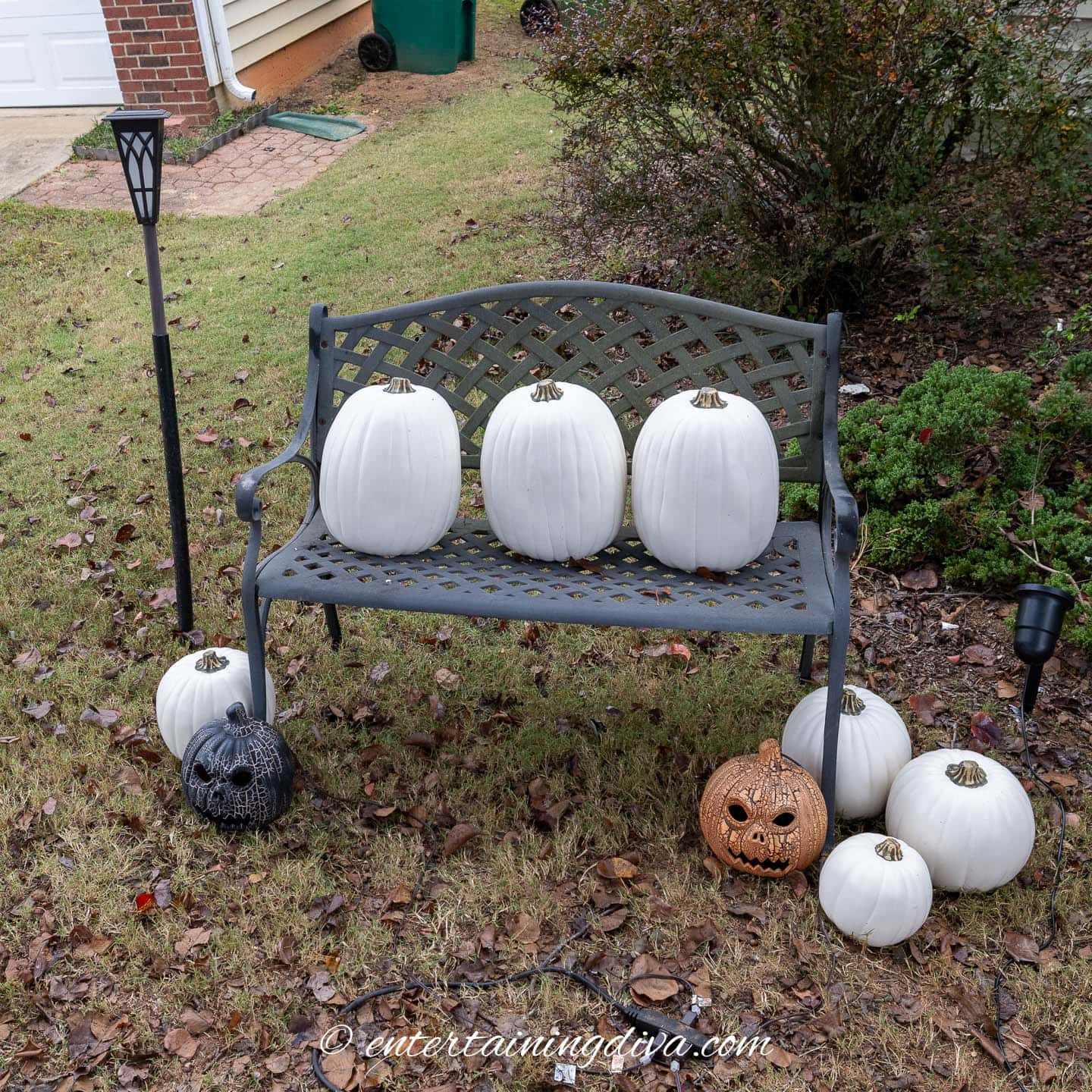 A bench with 3 large pumpkins on it and more pumpkins around the bottom