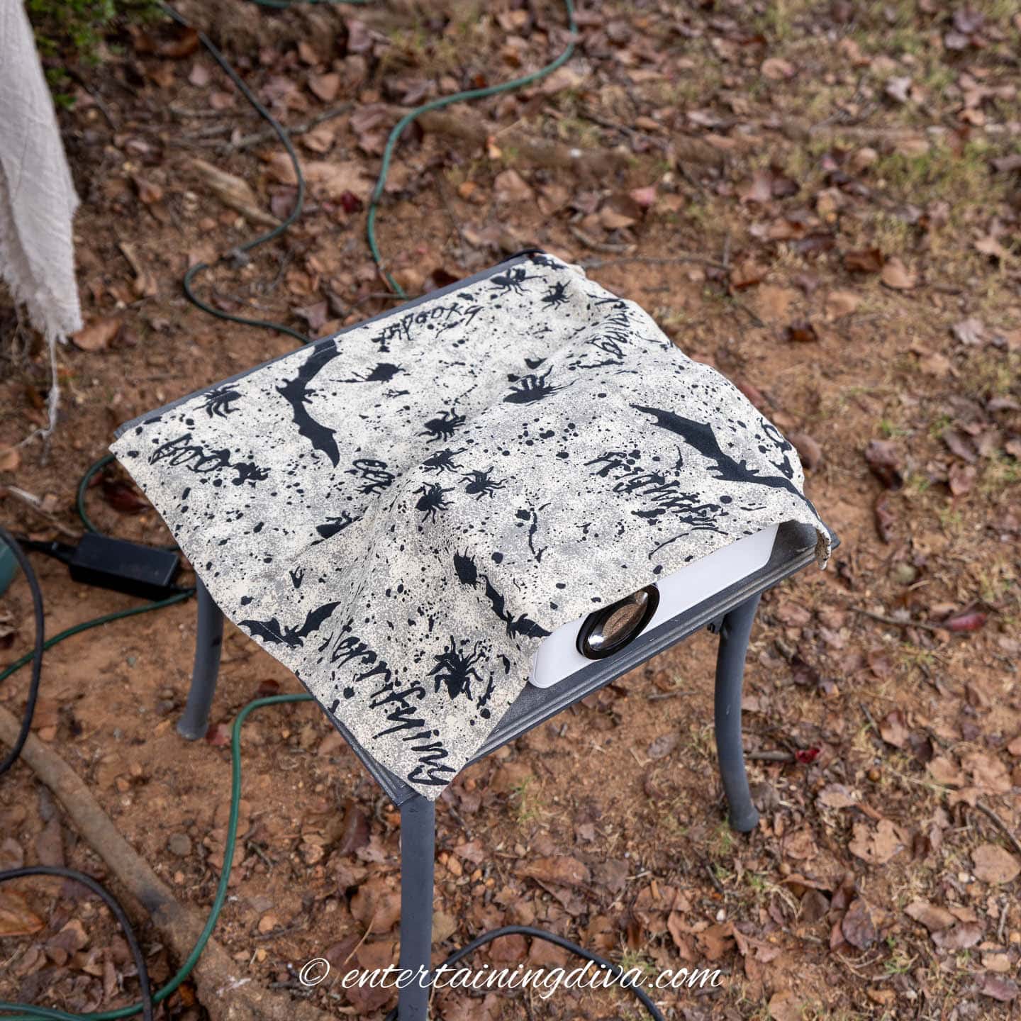 A projector covered with a Halloween tablecloth on a small table