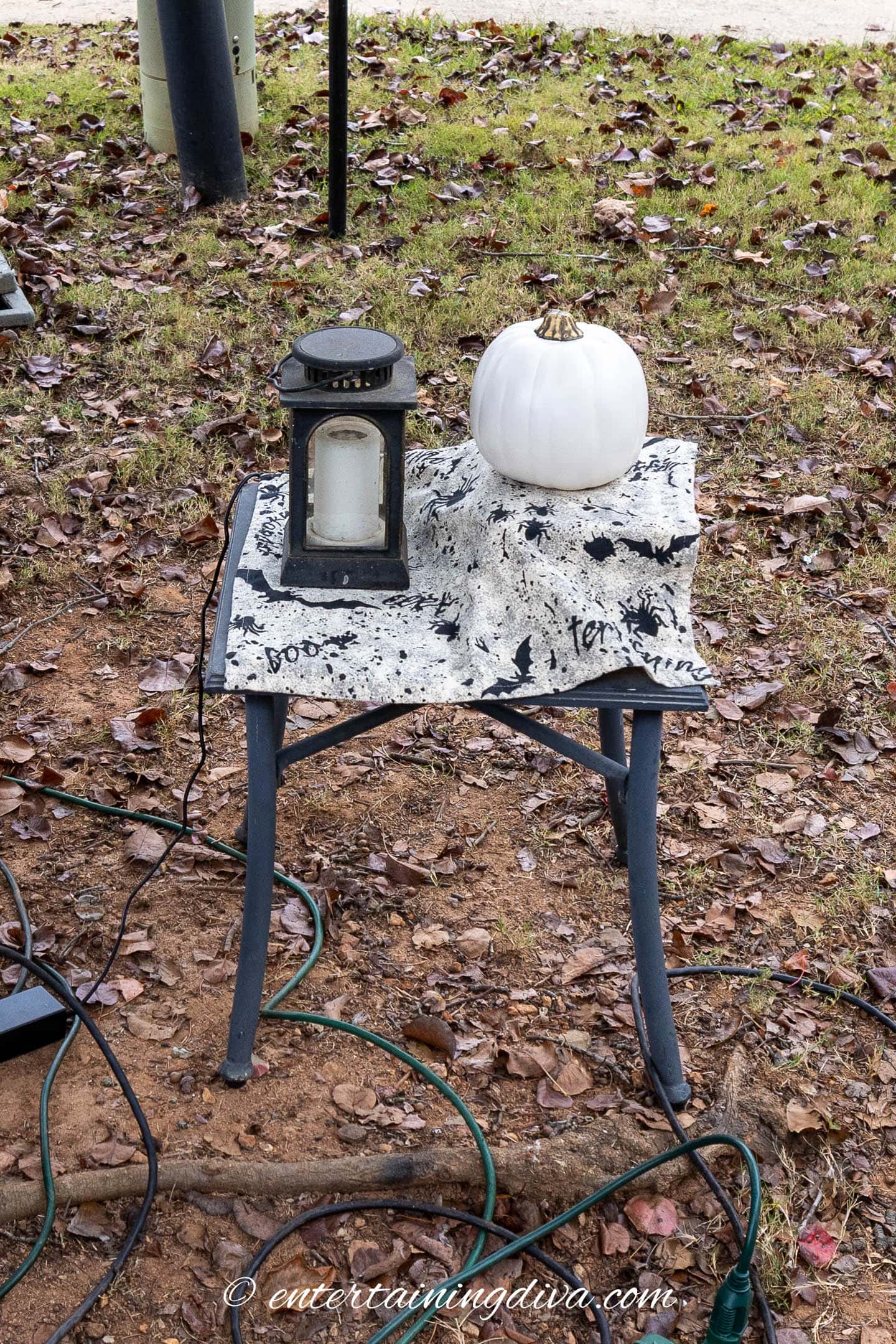 A projector covered with a Halloween tablecloth, a lantern and a small artificial pumpkin