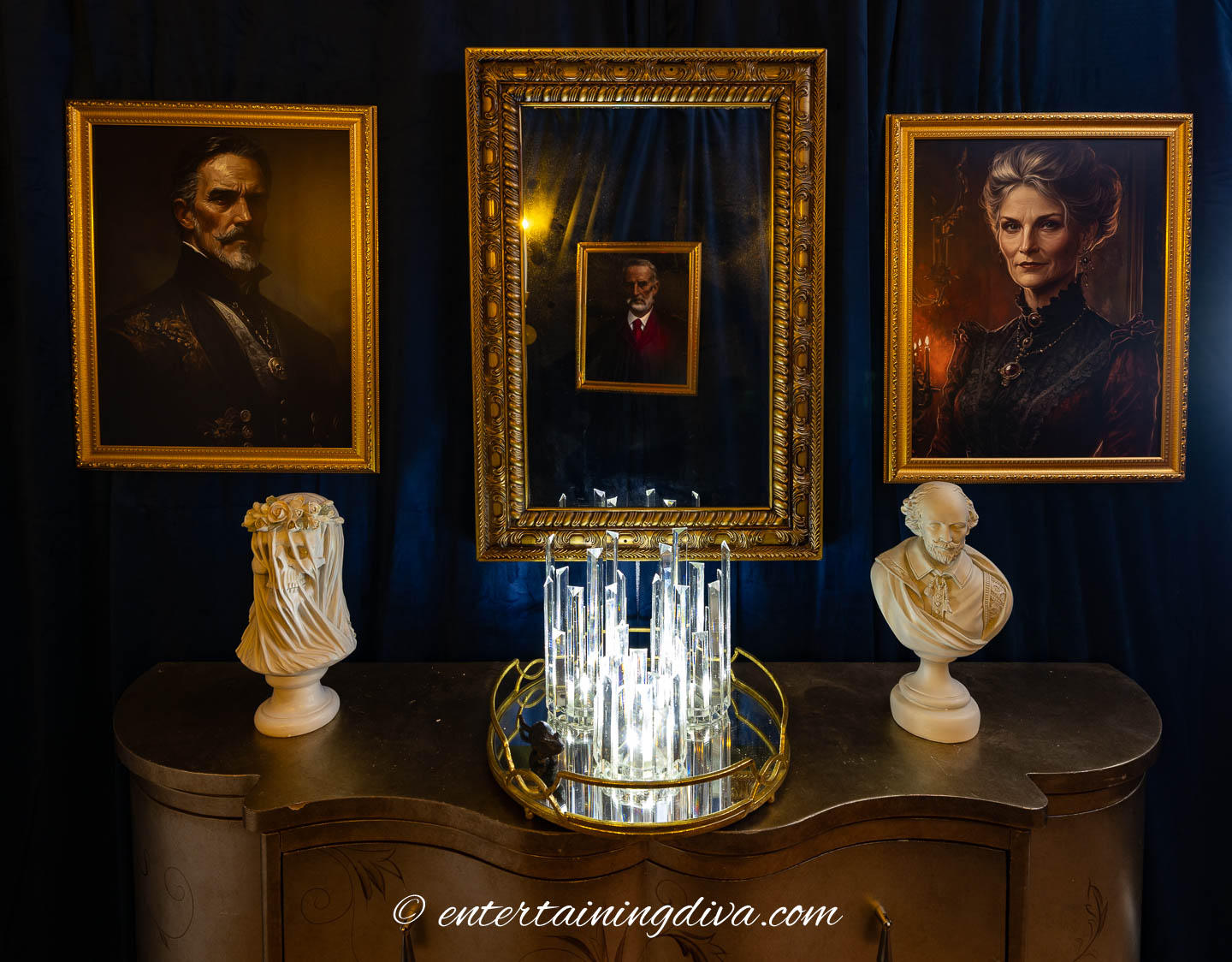 Two spooky portraits and a mirror hung over a console table with 2 busts on it