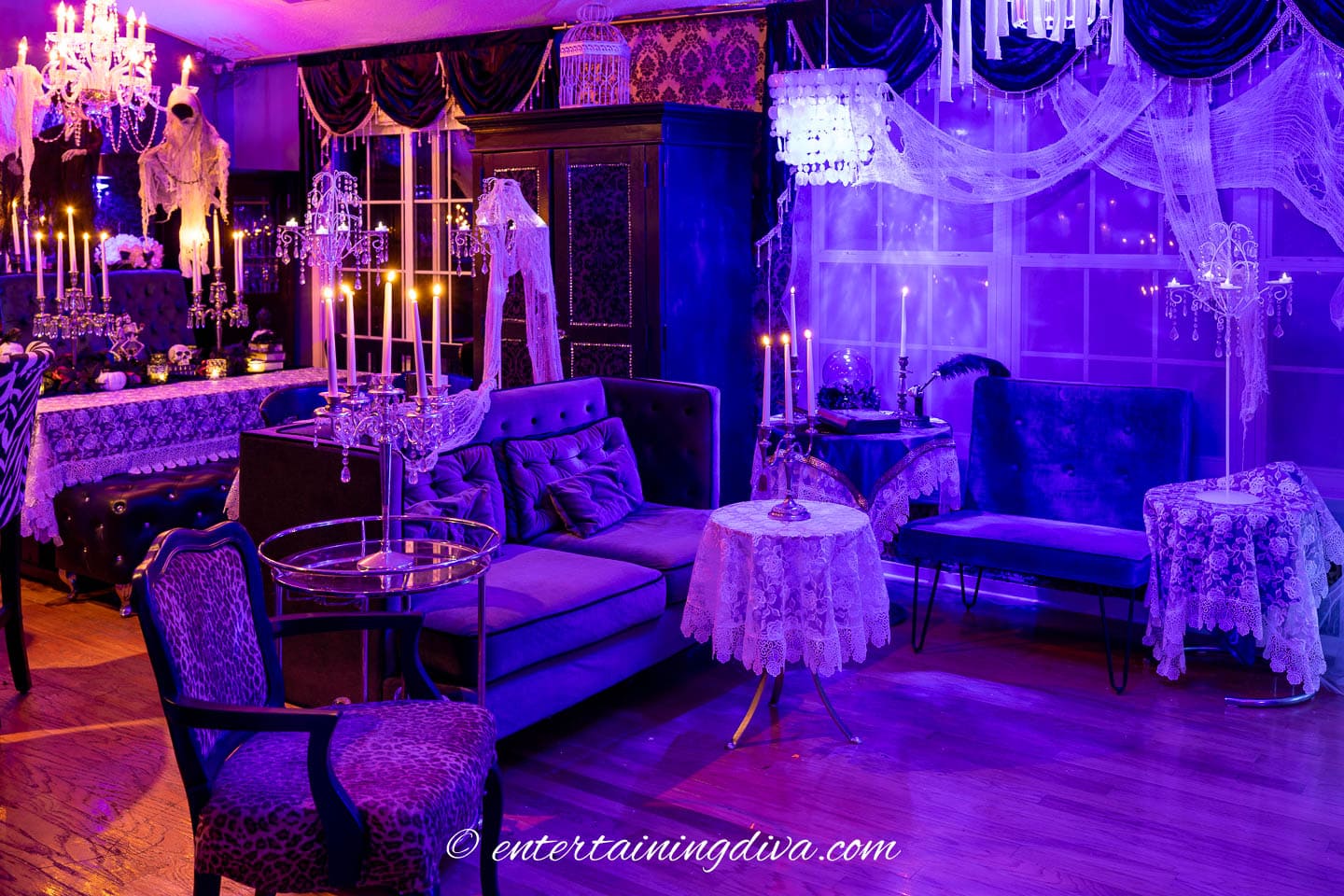 A living room decorated like a haunted mansion with lots of candles and creepy cloth ghosts