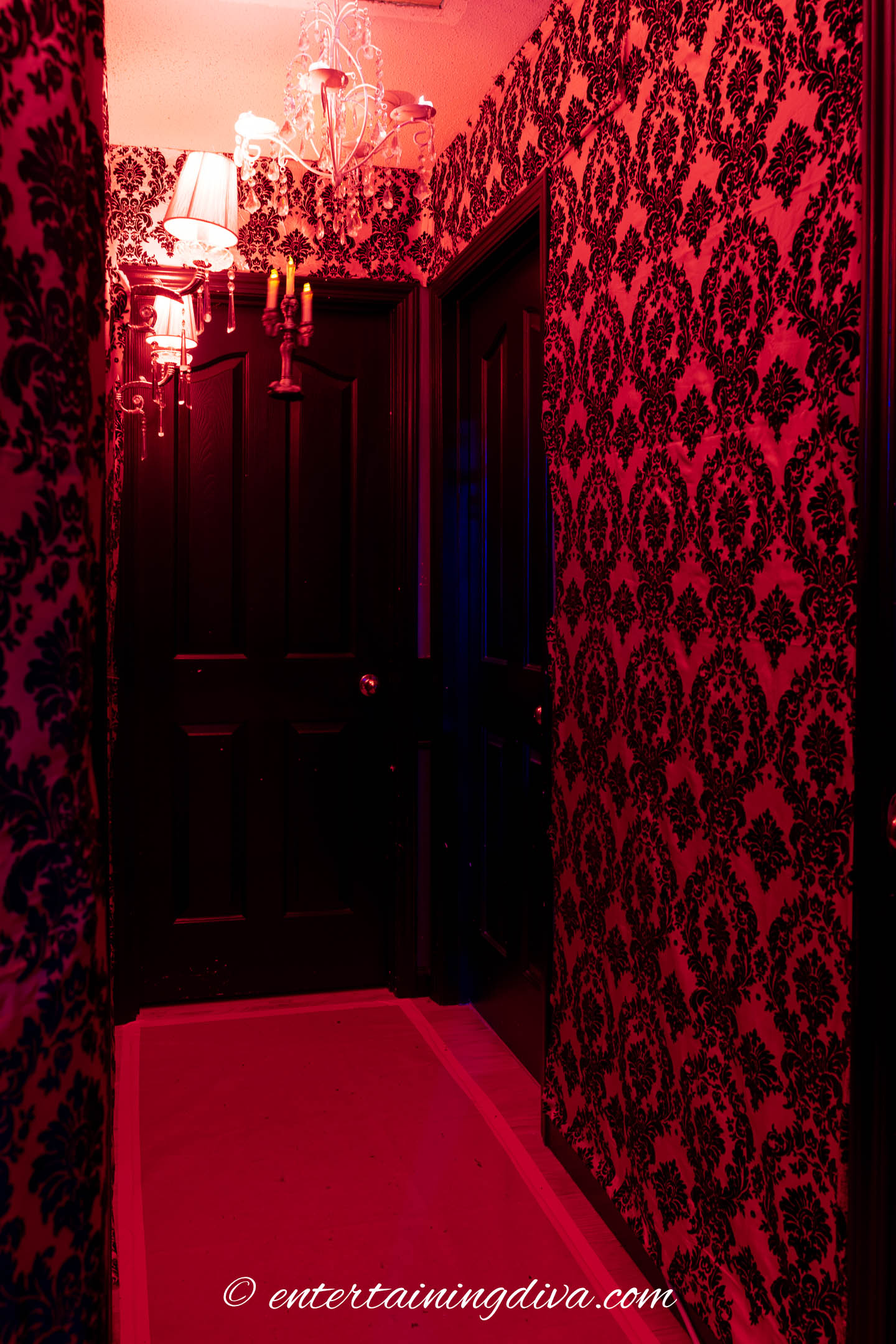 a floating candelabra hung at the end of a red and black hallway