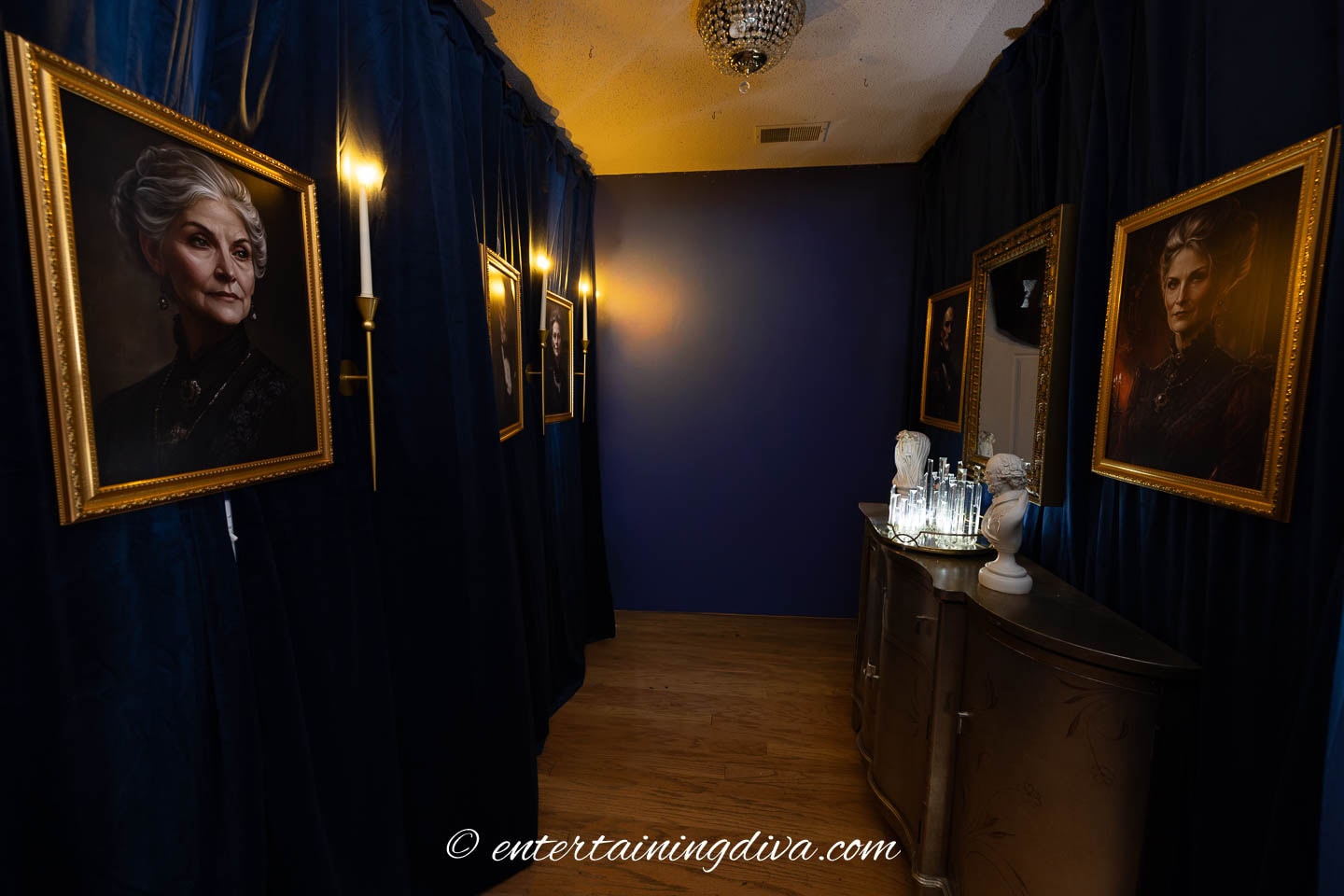 Spooky portraits hung on either side of a hallway with candles in between