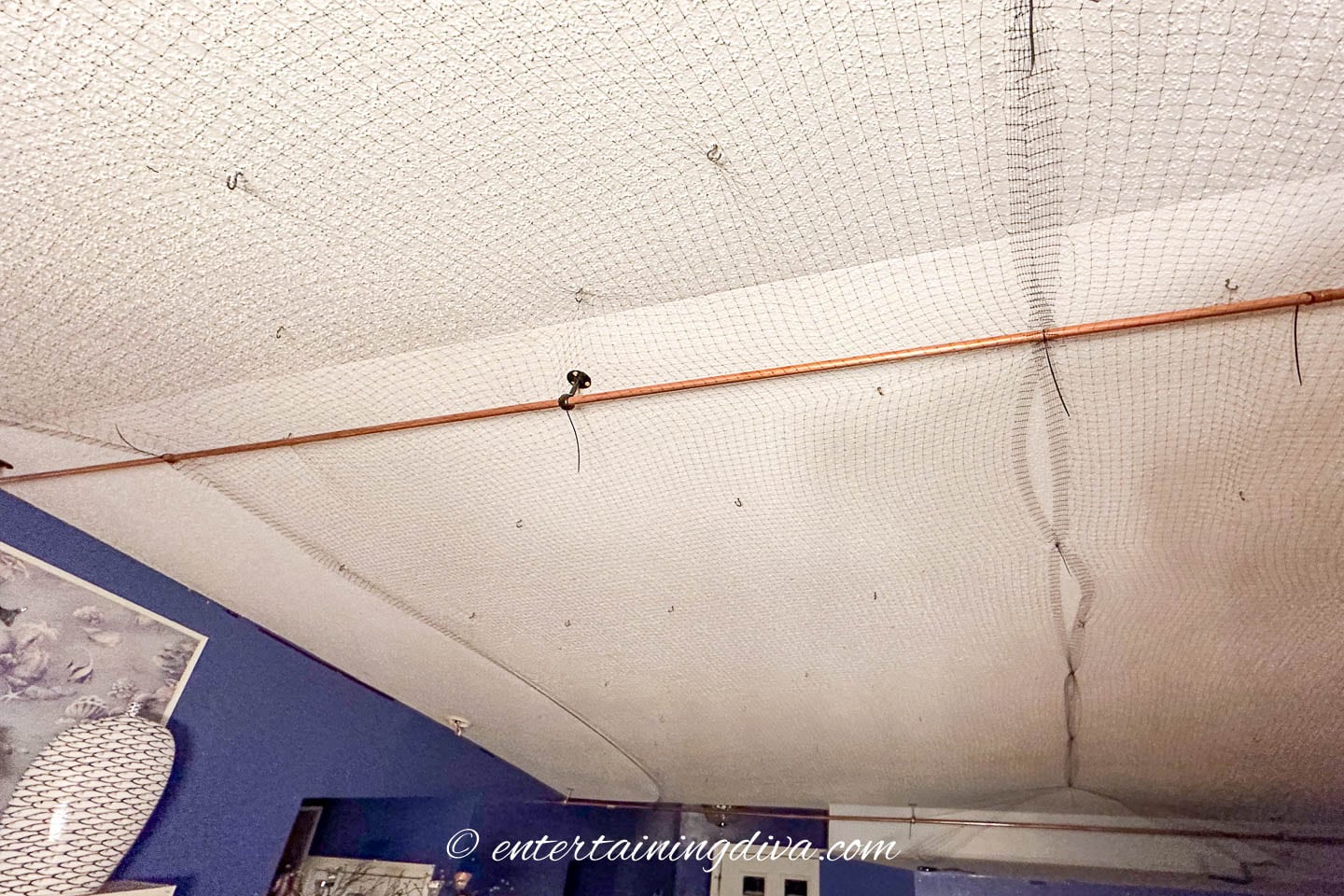 black mesh pulled tight across 2 curtain rods installed on the ceiling