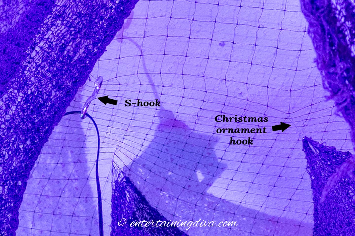 Creepy cloth hung from black mesh on the ceiling using an S-hook and a Christmas ornament hook