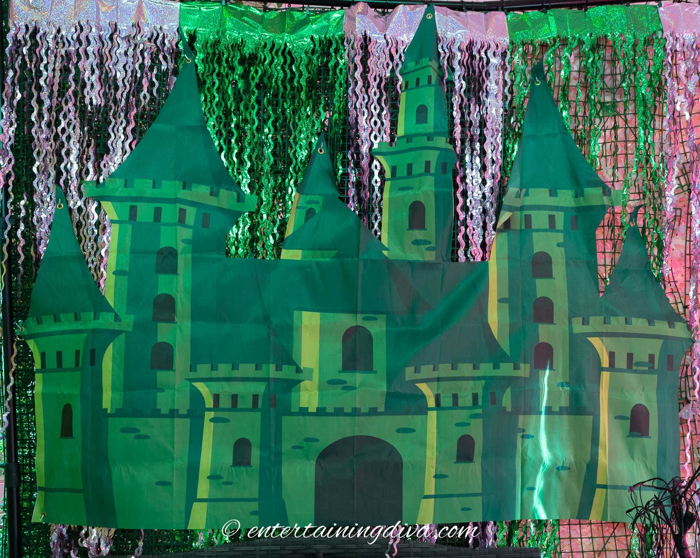 Large green castle illustration displayed as a backdrop, surrounded by silver and green decorative streamers. The website