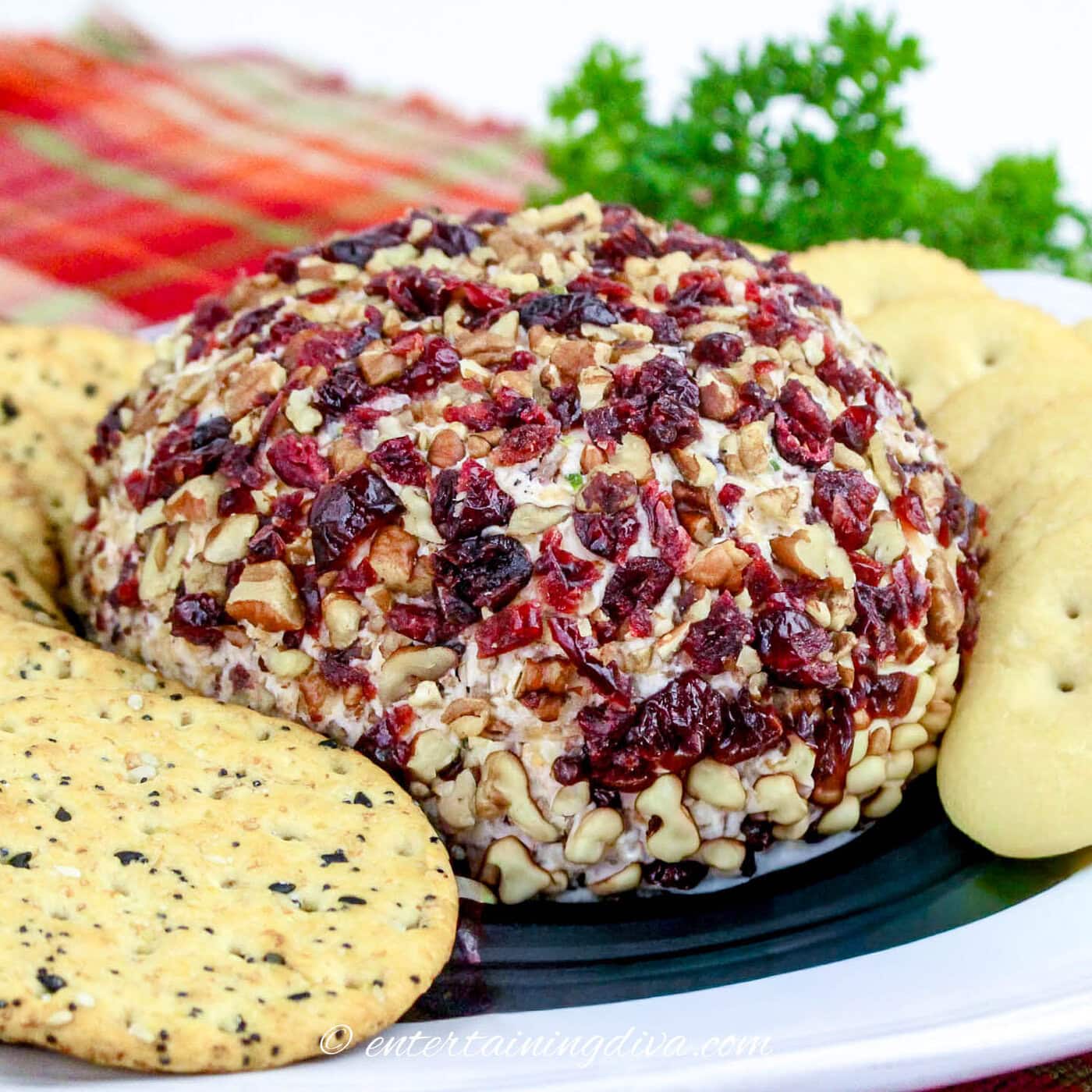 close up of cranberry pecan cheese ball on a plate with crackers
