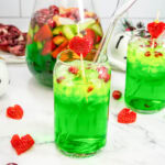 A close up of 2 glasses of green Grinch sangria with strawberry heart garnish