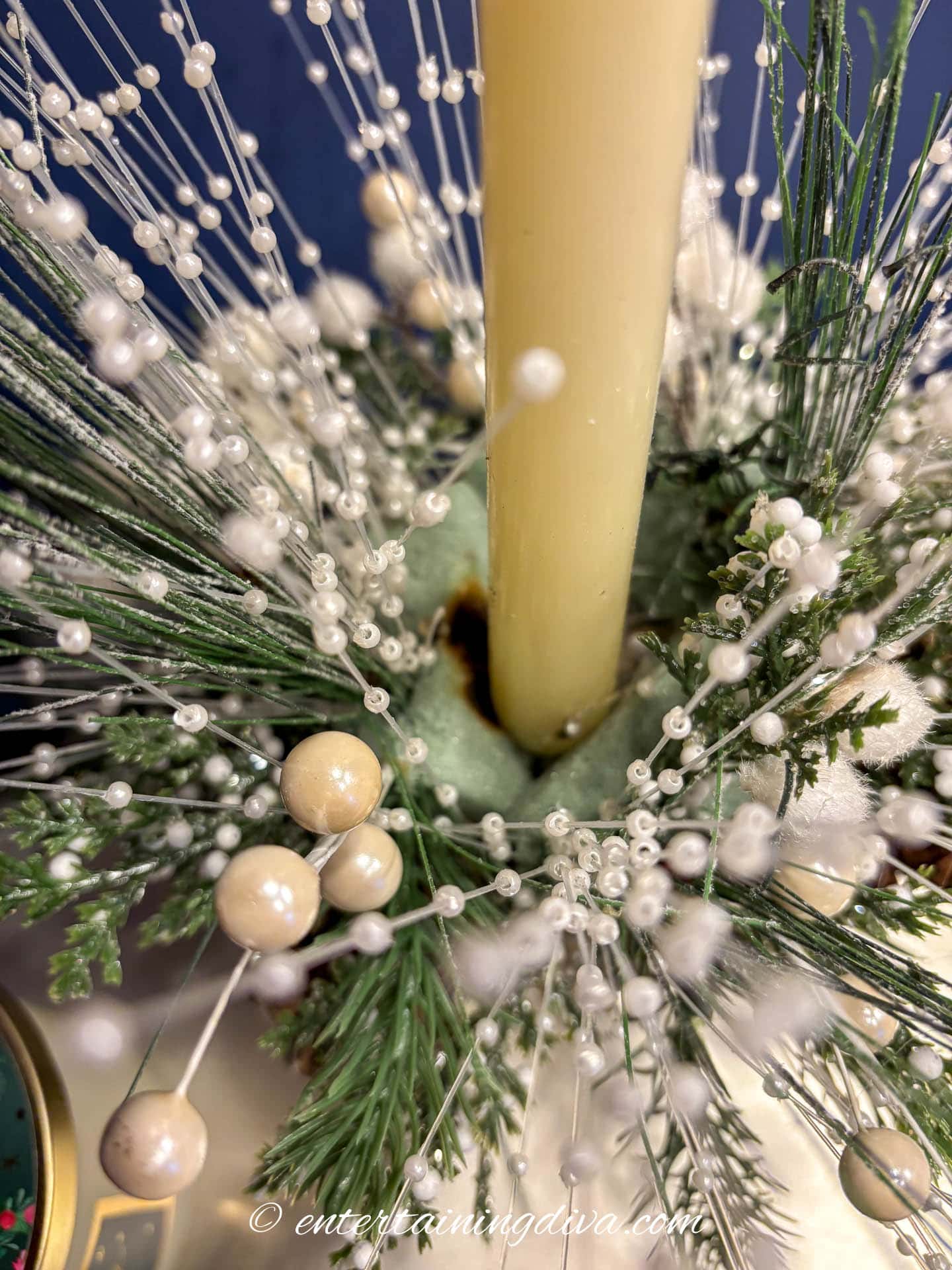 Close up of the candle between foam pieces on top of a small DIY Christmas ornament centerpiece