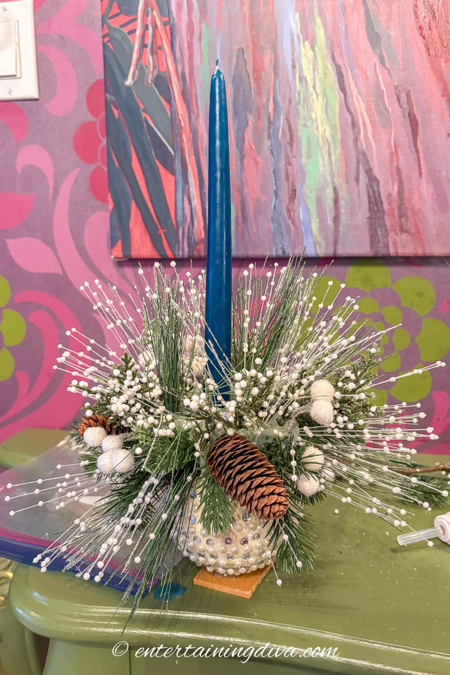 A blue candle in a small DIY Christmas ornament centerpiece