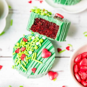 Close up of a Grinch cake puck with a bite taken out of it showing the red velvet cake inside