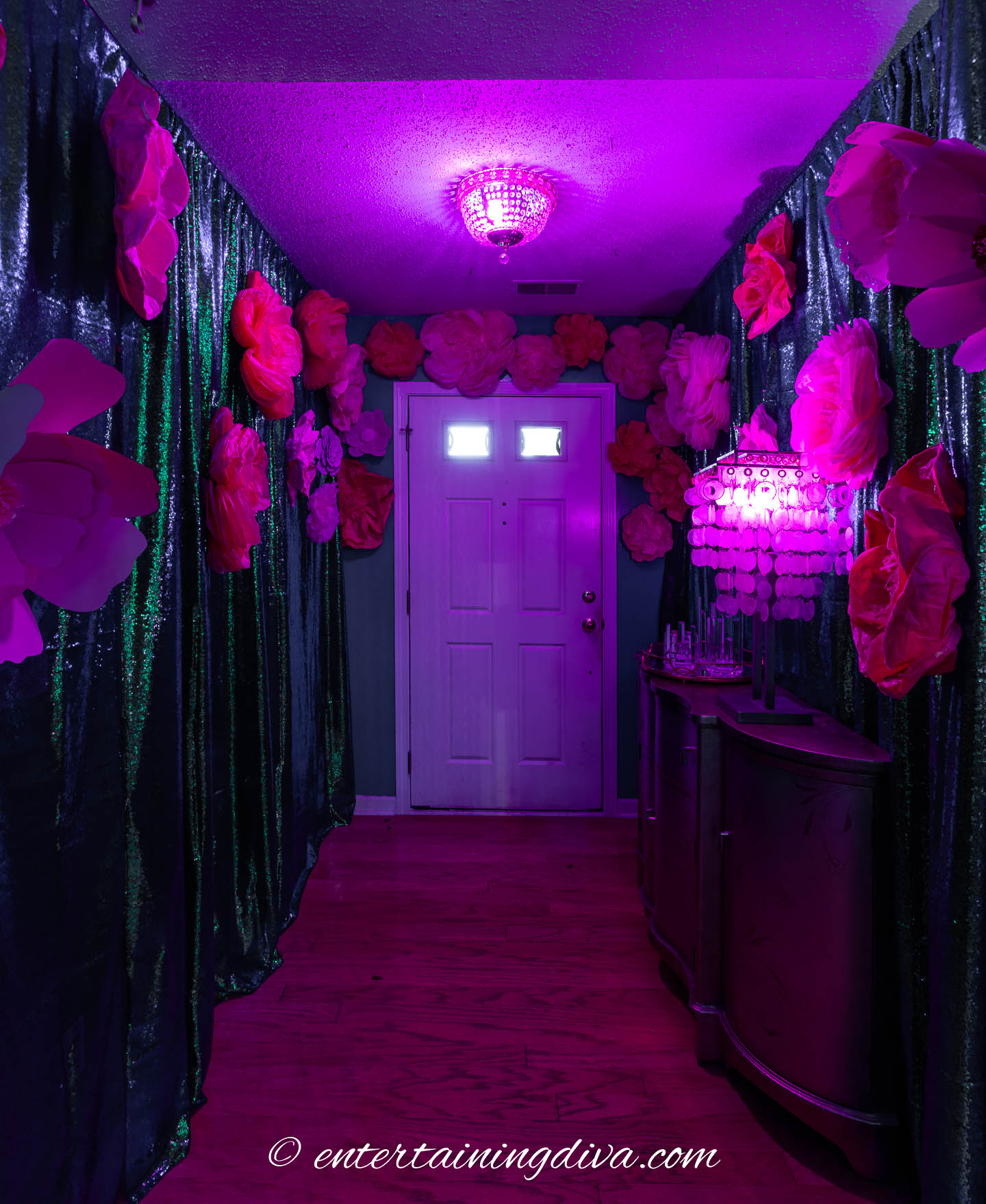 The entrance to a Wicked party decorated with green sequin curtains and large paper flowers