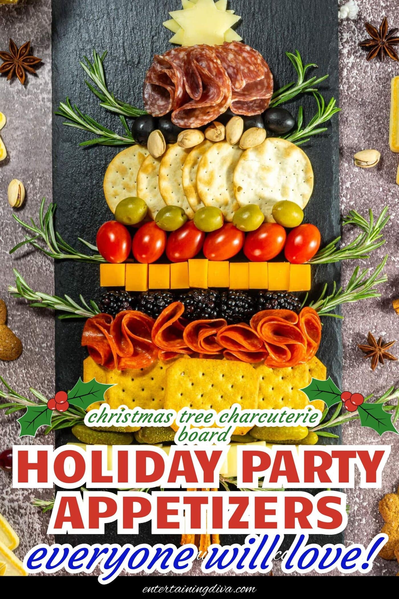A Christmas tree-shaped charcuterie board with assorted crackers, cheeses, meats, tomatoes, olives, nuts, and rosemary sprigs arranged on a black slate.