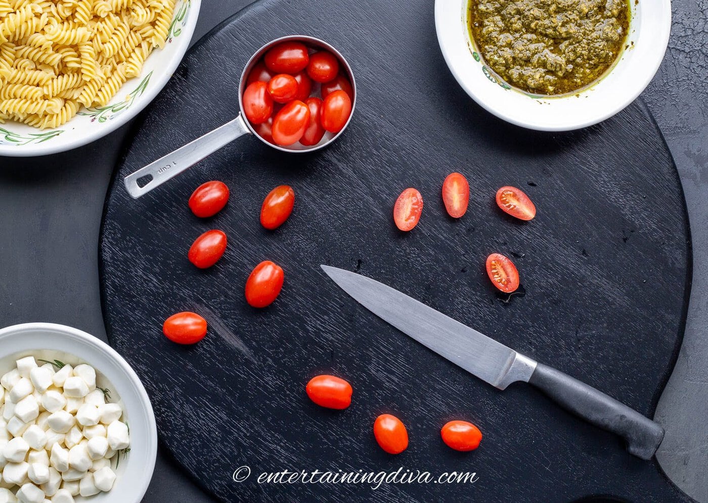 Grape tomatoes on a chopping board with a chef knife