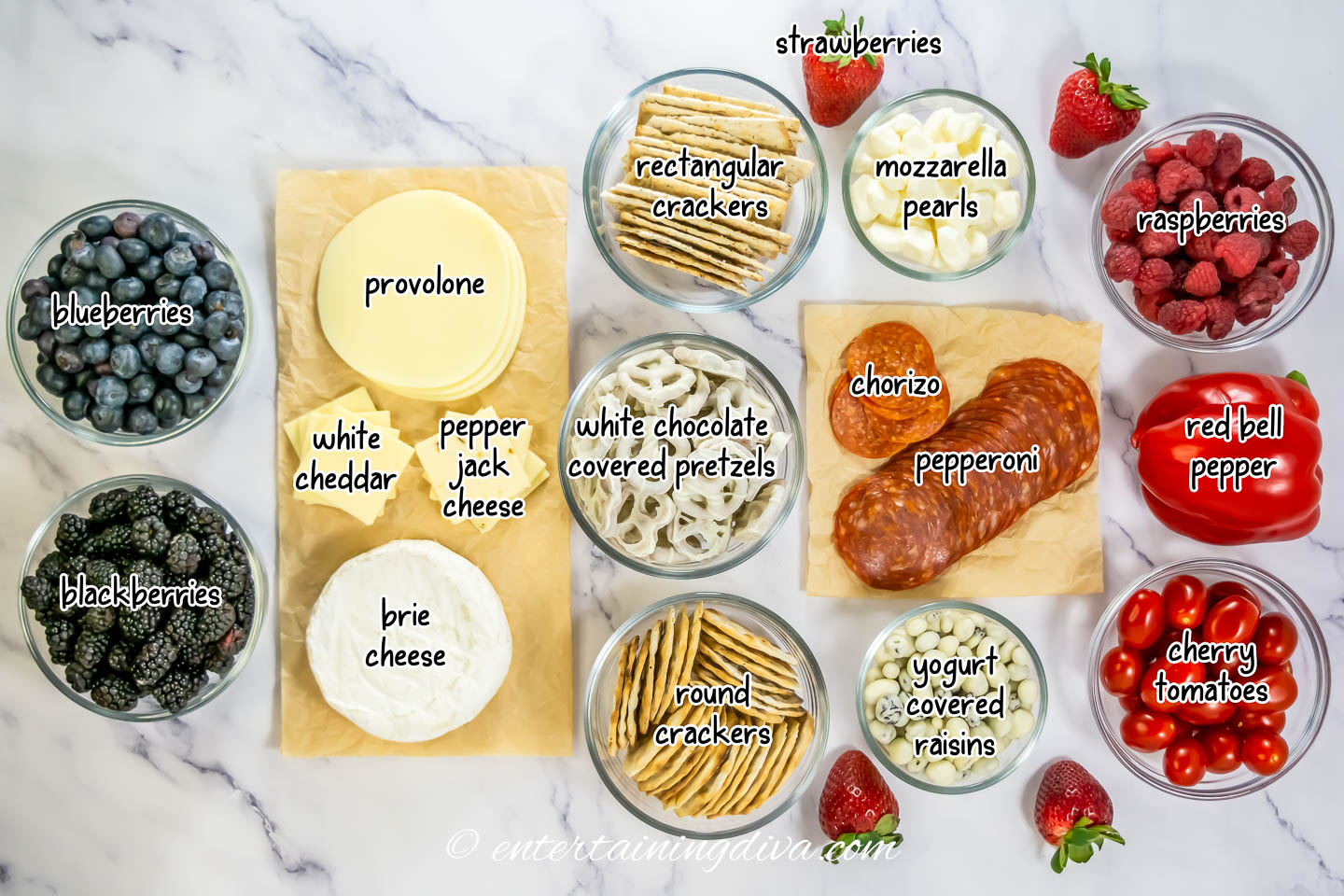 4th of July charcuterie board ingredients - blueberries, blackberries, provolone, white cheddar, pepper jack cheese, brie, crackers, white chocolate covered pretzels, strawberries, mozzarella pearls, chorizo, pepperoni, yogurt-covered raisins, raspberries, red bell pepper, cherry tomatoes