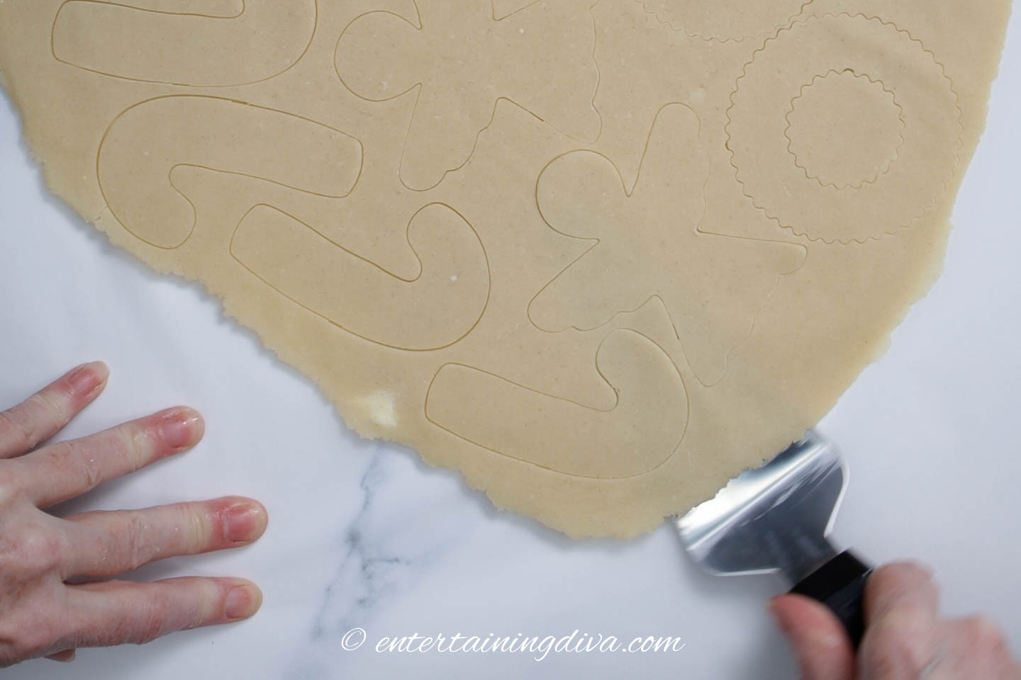 Removing the cut out angel cookies from the dough