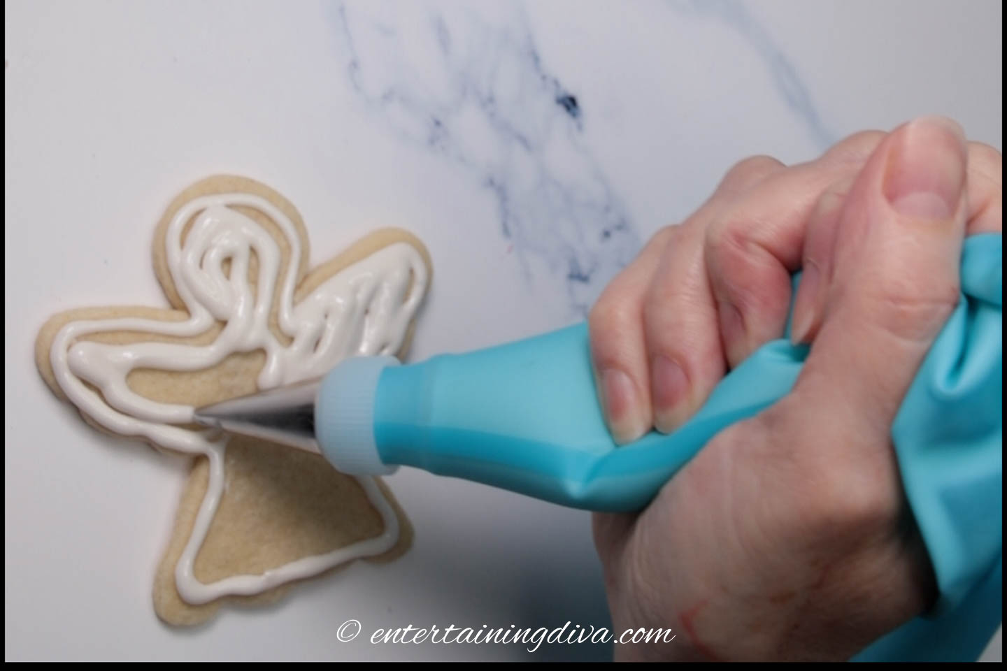 Christmas angel sugar cookie being flooded with white royal icing