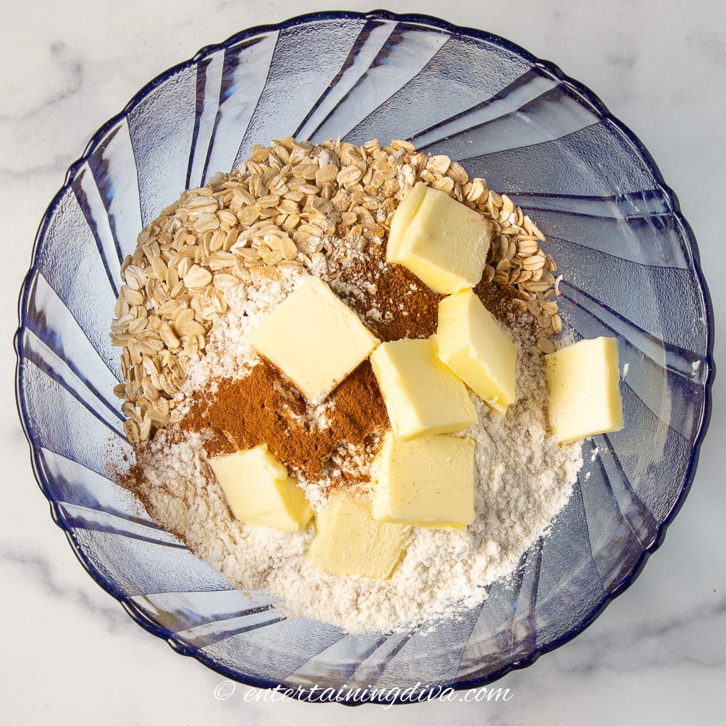 Bowl with rolled oats, flour, cinnamon, nutmeg and sliced butter