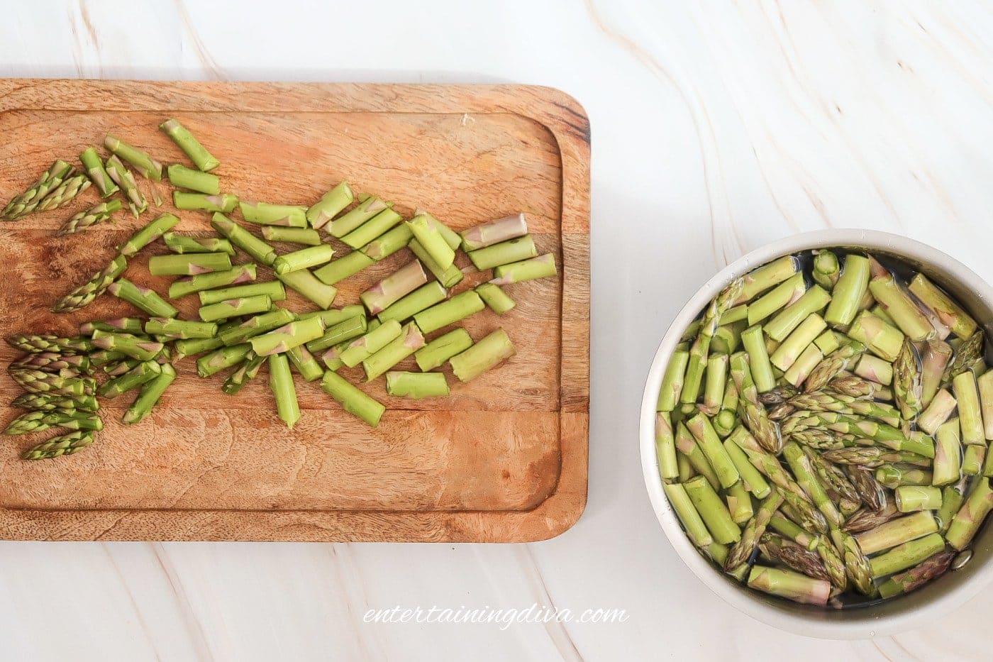 Chopped asparagus on a cutting board and in a pot beside it