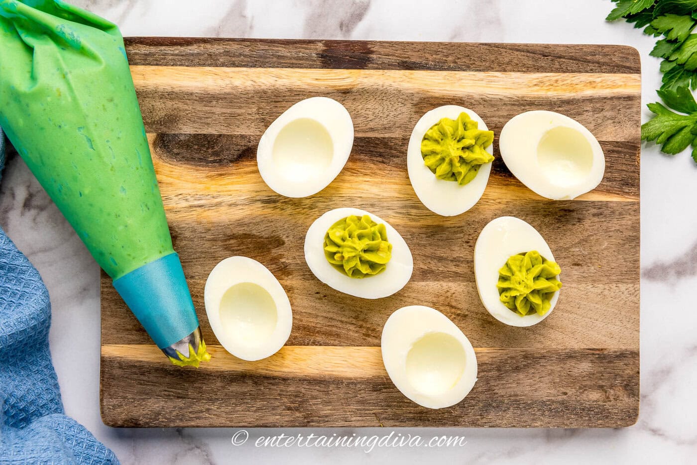 6 boiled egg halves on a cutting board with avocado filling piped into half of them