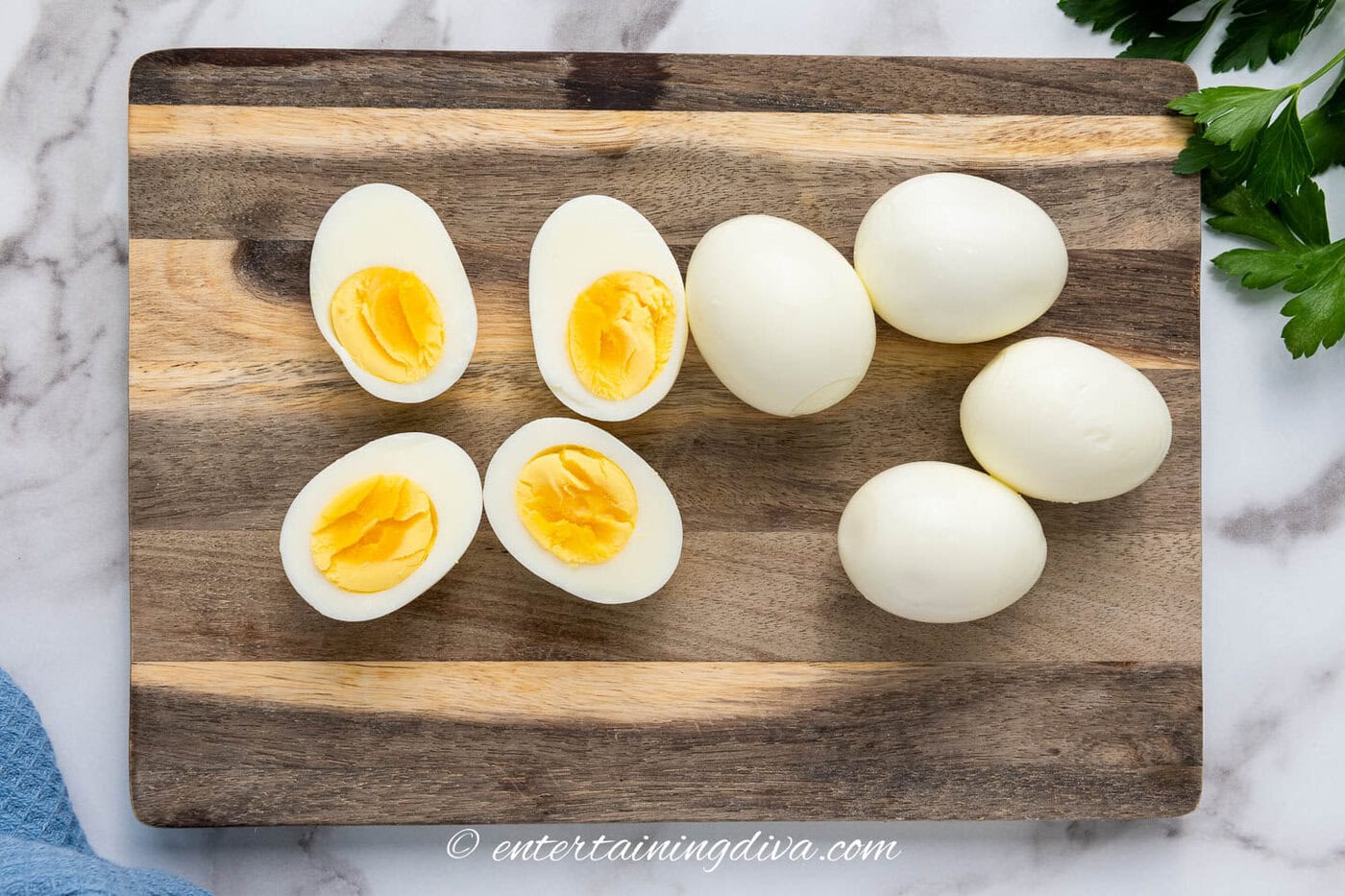 hard boiled eggs on a cutting board with 2 of them cut in half