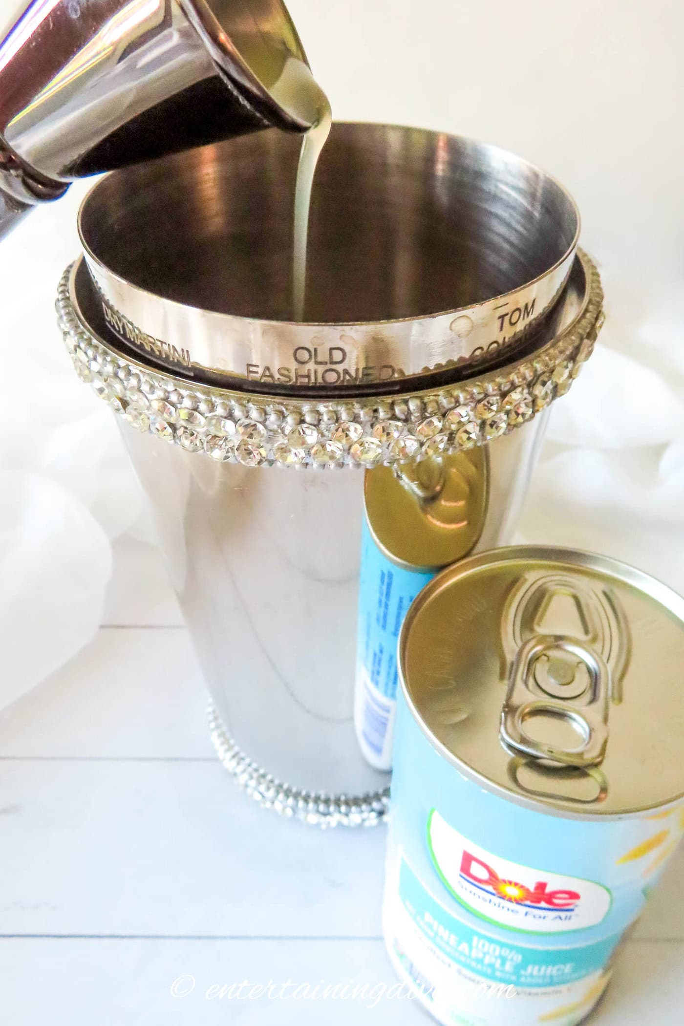 pineapple juice being poured into a cocktail shaker