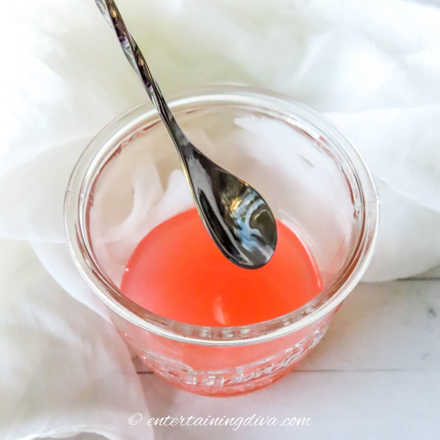 an Azalea cocktail being stirred in a glass cocktail shaker