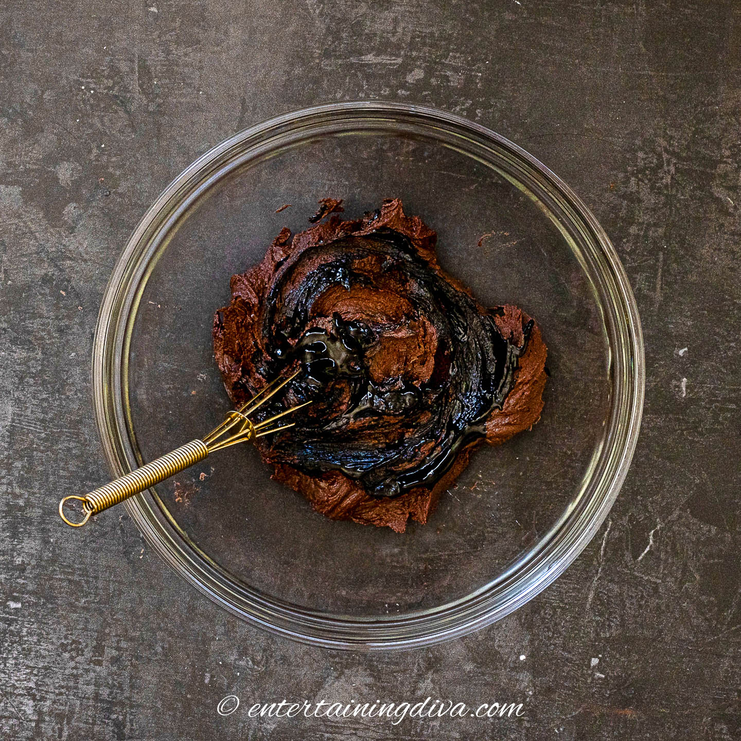 chocolate buttercream frosting in a glass bowl with black food coloring in it