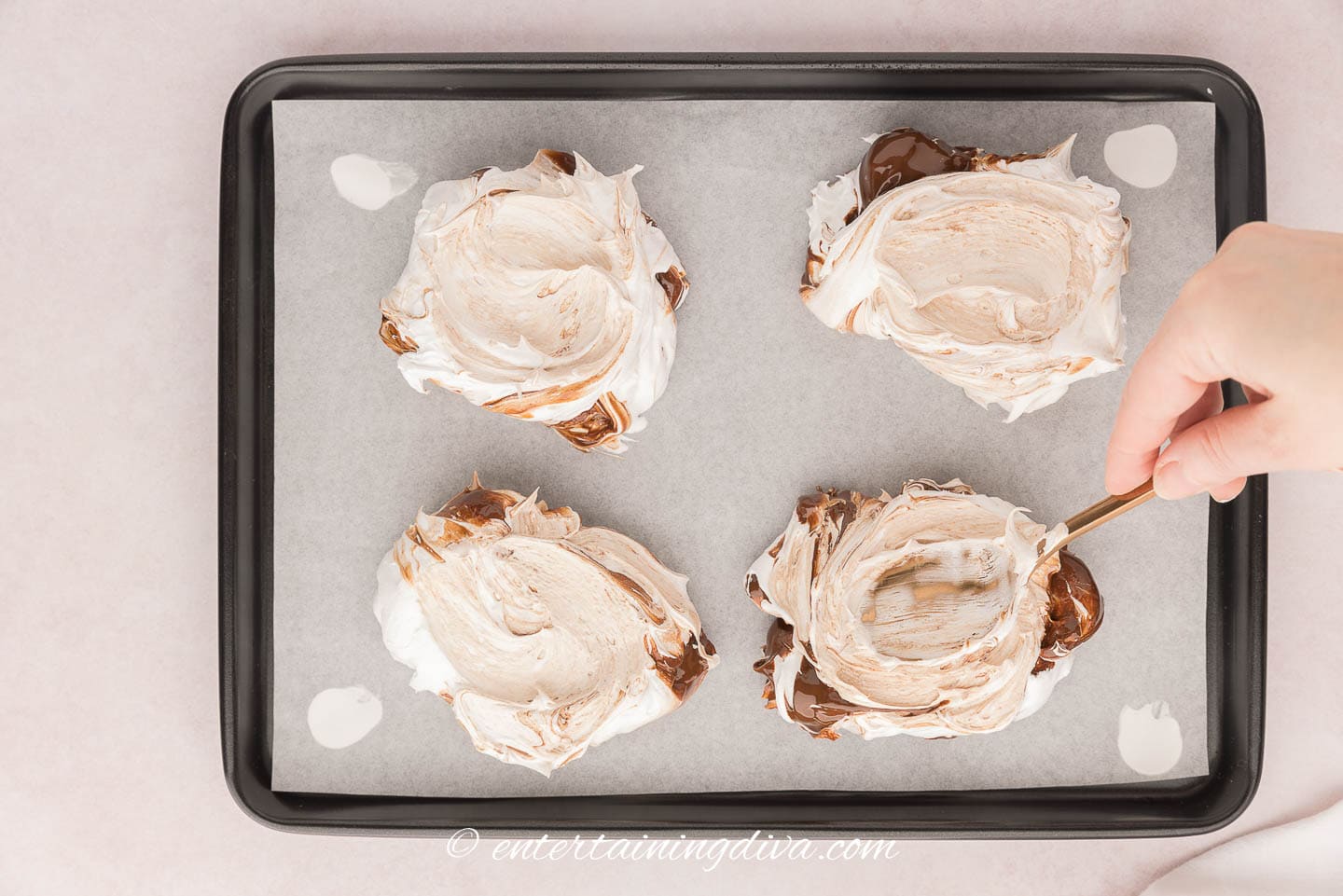 Spoon creating a dip in a pavlova on a baking sheet