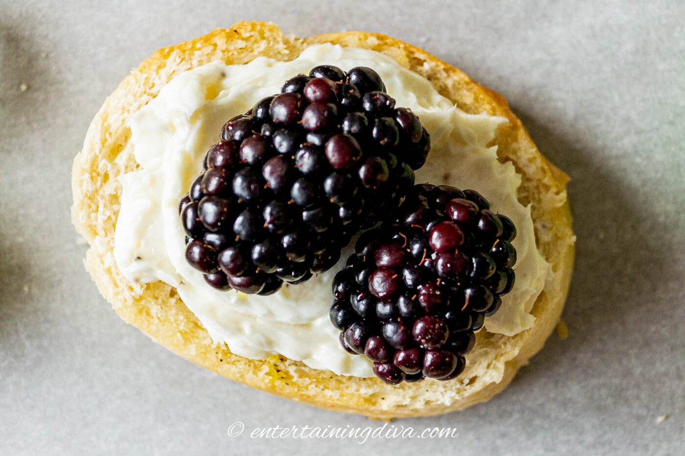 close up overhead picture of 2 blackberries with whipped goat cheese on crostini