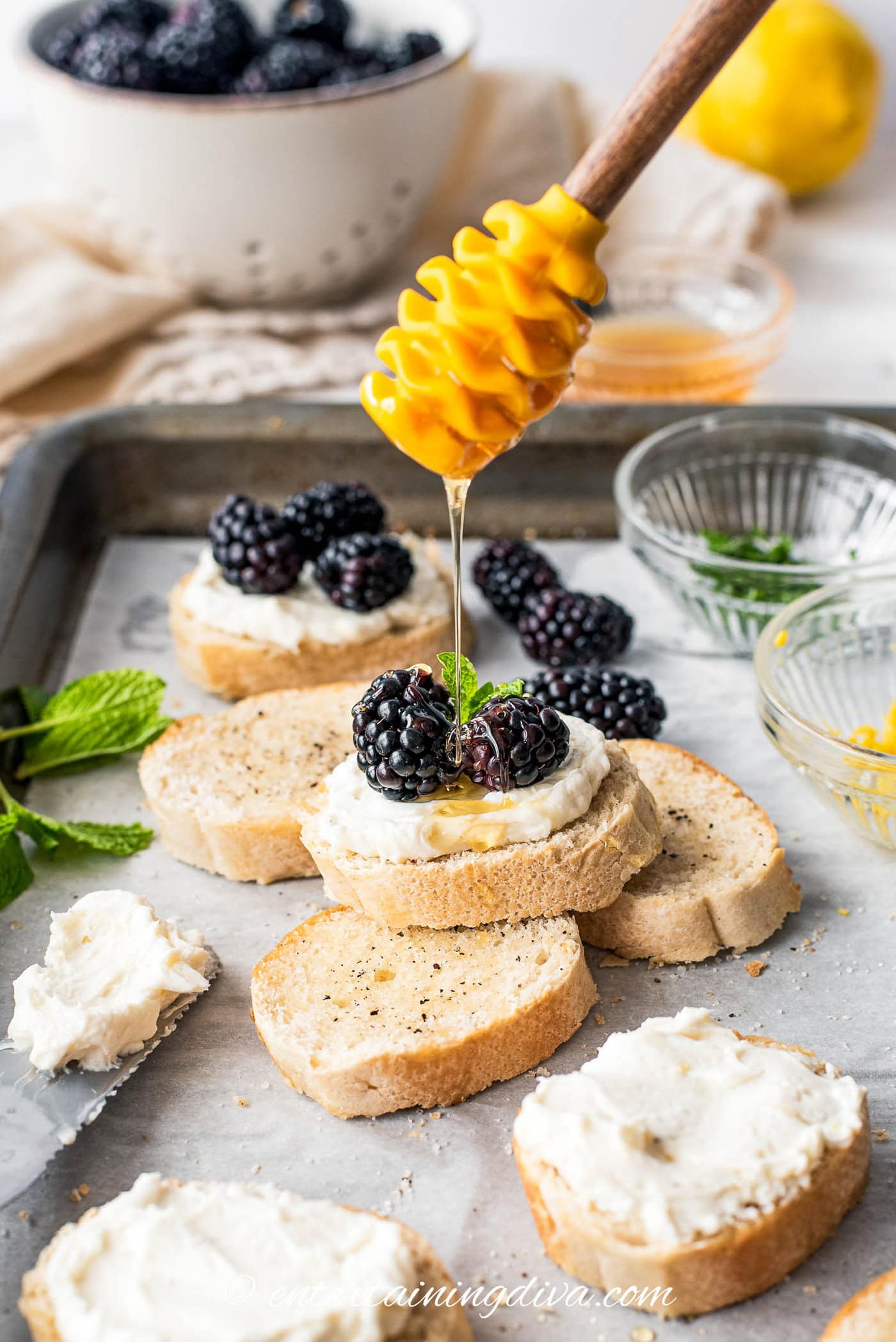honey being drizzled on a blackberry goat cheese crostini